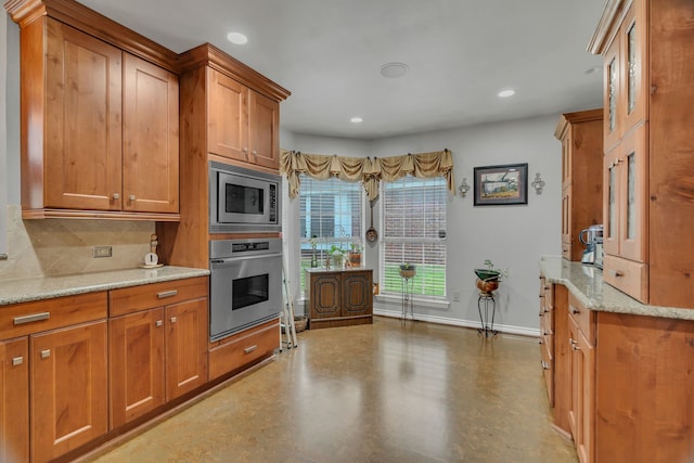 kitchen featuring backsplash, concrete flooring, light stone counters, and appliances with stainless steel finishes