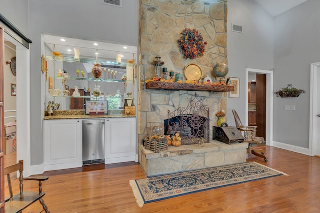 living room with a fireplace, light hardwood / wood-style flooring, and a high ceiling