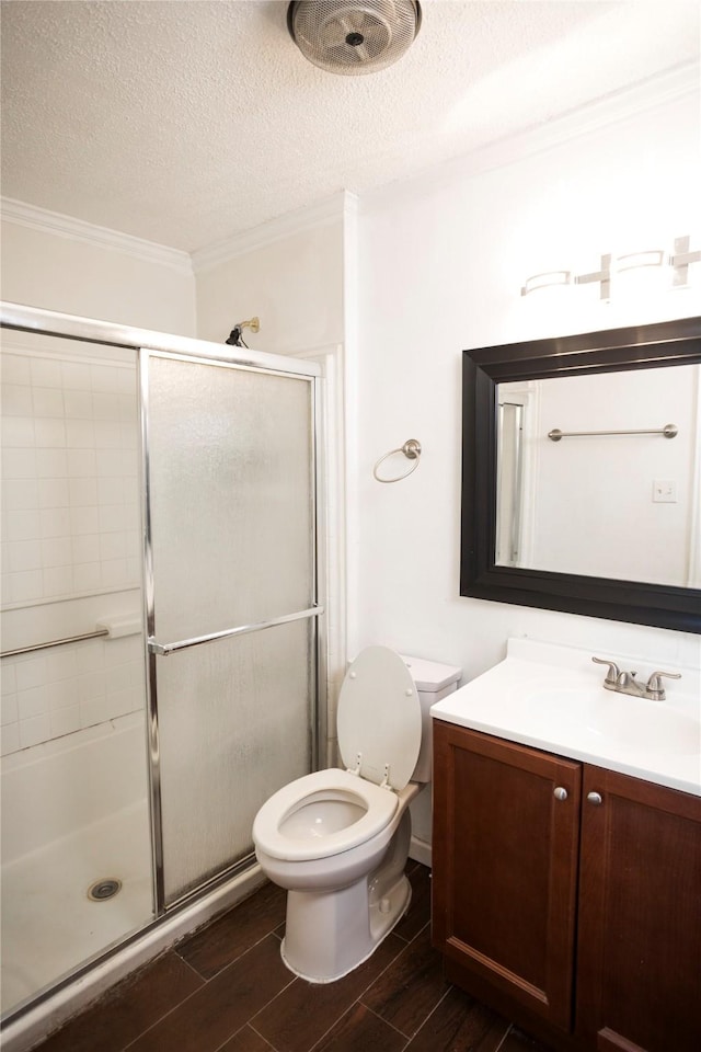 bathroom with vanity, toilet, a shower with door, crown molding, and a textured ceiling