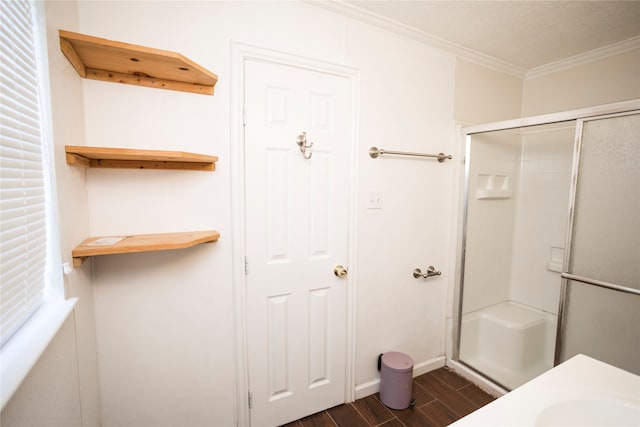 bathroom with wood-type flooring, a shower with door, and ornamental molding