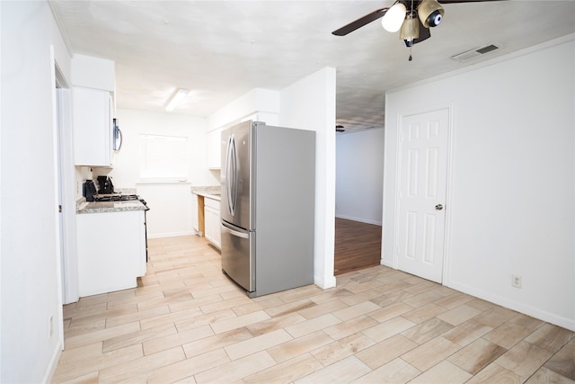 kitchen featuring stainless steel appliances, ceiling fan, white cabinets, and light stone counters