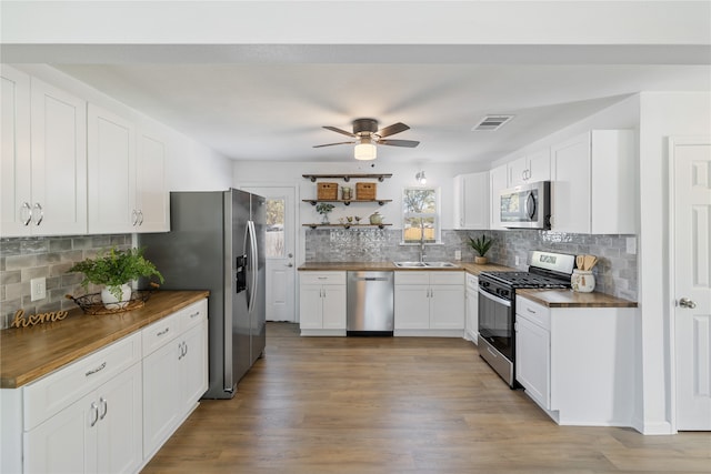 kitchen featuring wood counters, sink, white cabinetry, stainless steel appliances, and backsplash