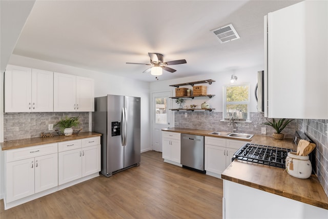 kitchen with white cabinets, sink, light hardwood / wood-style flooring, appliances with stainless steel finishes, and butcher block counters