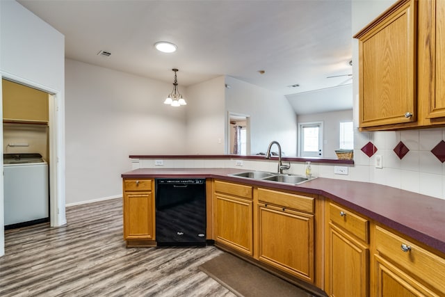 kitchen with washer / dryer, backsplash, black dishwasher, sink, and hardwood / wood-style flooring