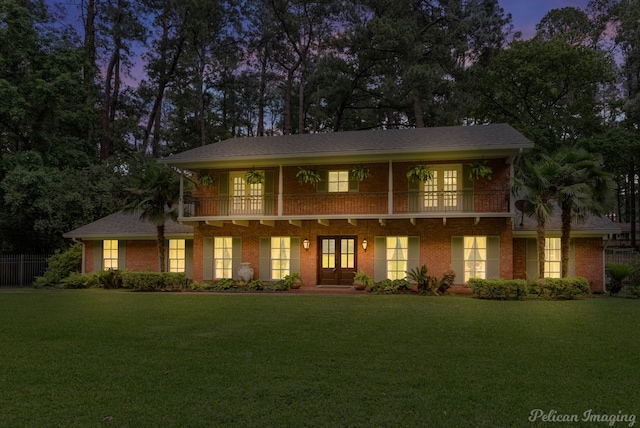 view of front facade featuring a lawn and a balcony