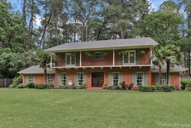 view of front of house featuring a front lawn, french doors, and a balcony