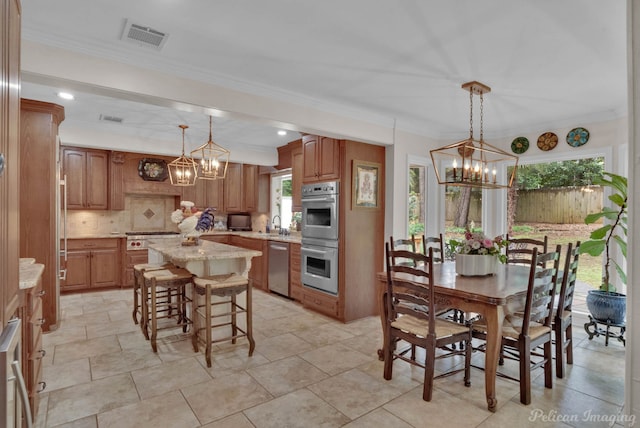 kitchen with pendant lighting, a wealth of natural light, a kitchen island, and appliances with stainless steel finishes