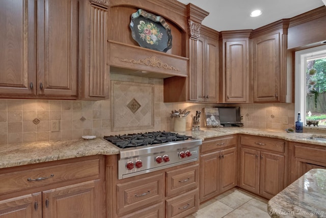 kitchen featuring light tile patterned flooring, stainless steel gas stovetop, tasteful backsplash, and light stone countertops