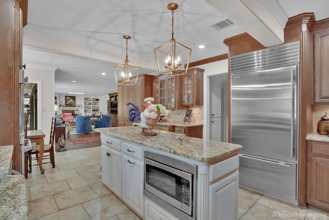 kitchen with a center island, built in appliances, backsplash, light stone countertops, and pendant lighting