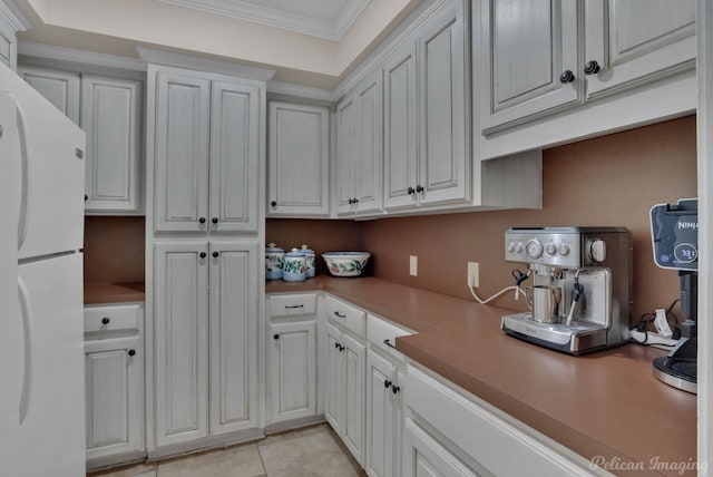 kitchen featuring light tile patterned flooring, white refrigerator, ornamental molding, and white cabinets