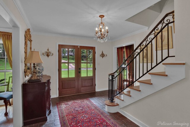 foyer entrance with ornamental molding, french doors, and an inviting chandelier