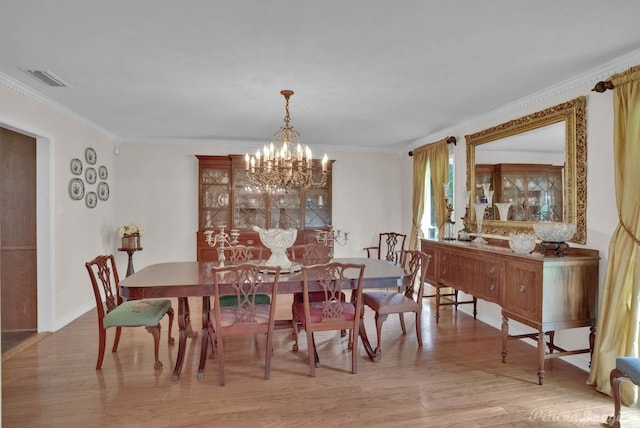 dining area featuring ornamental molding, light wood-type flooring, and a chandelier