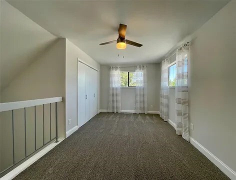 bonus room featuring ceiling fan and dark carpet