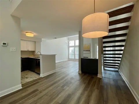 interior space featuring dark hardwood / wood-style flooring, white cabinetry, pendant lighting, and kitchen peninsula