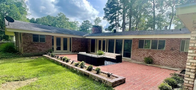 rear view of property with outdoor lounge area, a yard, a patio, and french doors