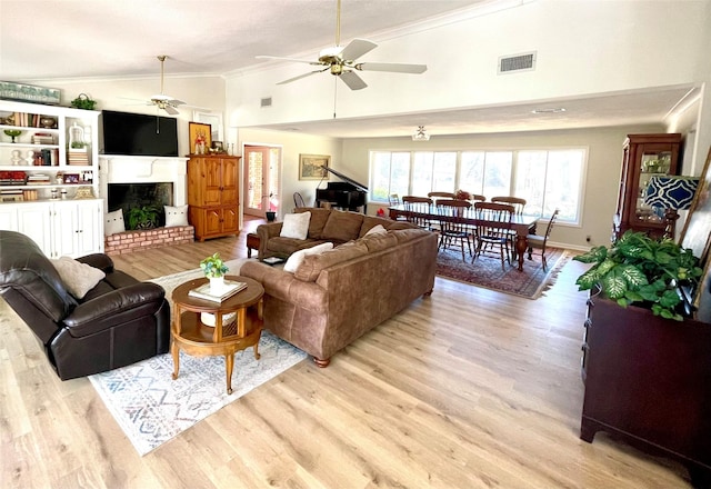 living room featuring high vaulted ceiling, a brick fireplace, ceiling fan, light wood-type flooring, and ornamental molding