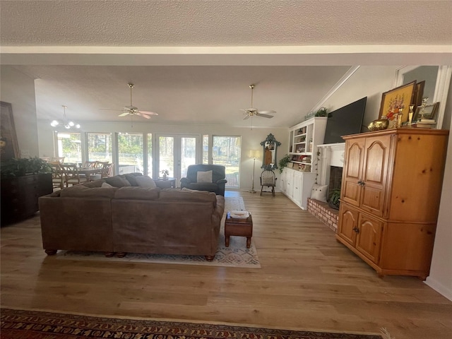 living room with a textured ceiling, ceiling fan with notable chandelier, light hardwood / wood-style flooring, and lofted ceiling