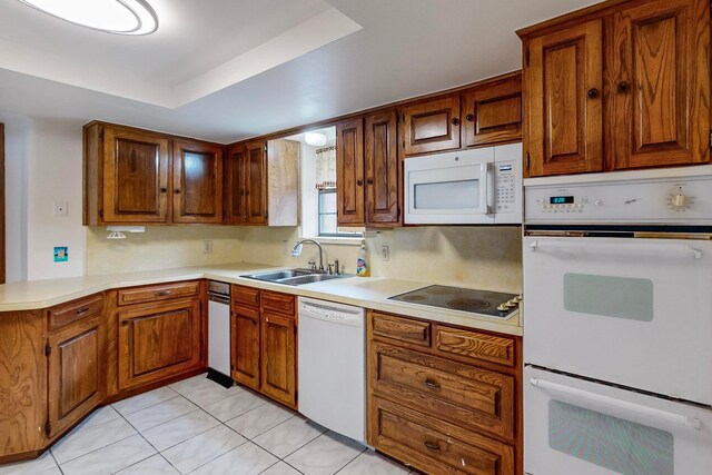 kitchen featuring sink, white appliances, a tray ceiling, and light tile patterned flooring