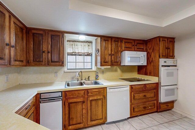 kitchen featuring tasteful backsplash, light tile patterned floors, a raised ceiling, sink, and white appliances