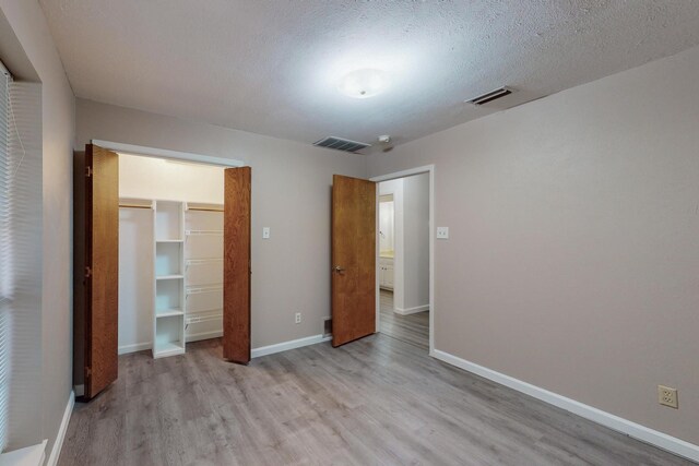 unfurnished bedroom with a closet, a textured ceiling, and light hardwood / wood-style floors