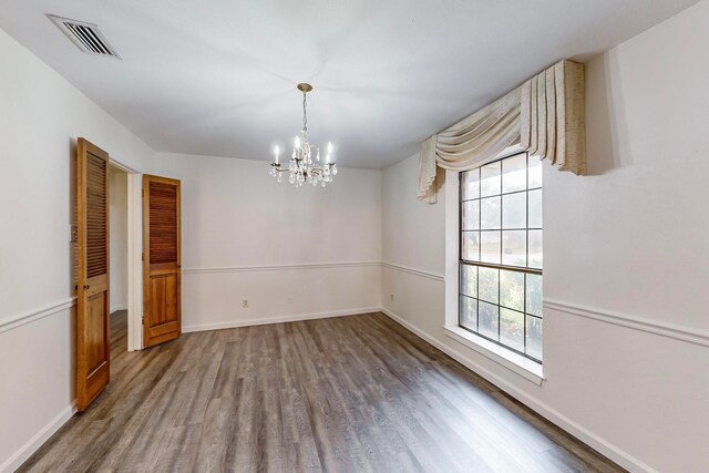 unfurnished dining area featuring hardwood / wood-style flooring and an inviting chandelier