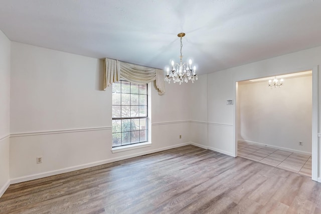 spare room with a chandelier and hardwood / wood-style floors