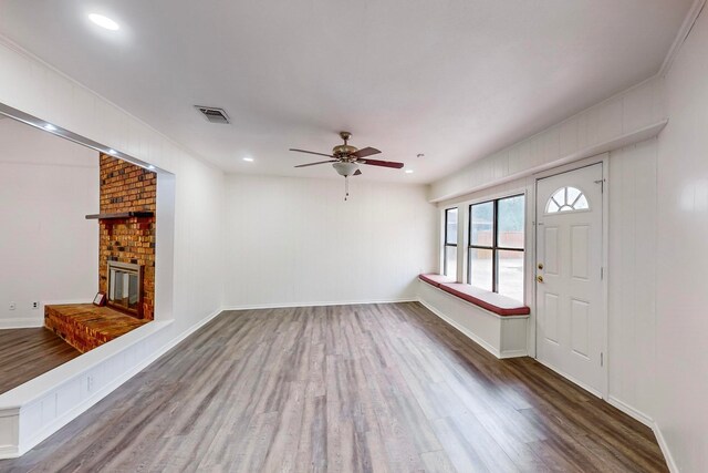 unfurnished living room featuring dark wood-type flooring, ceiling fan, and a fireplace