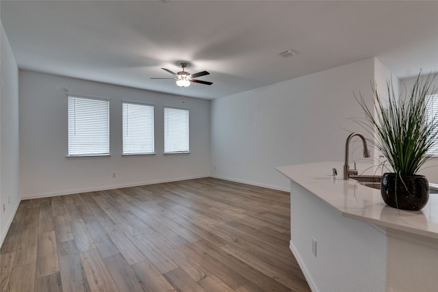 interior space featuring ceiling fan, sink, and light wood-type flooring