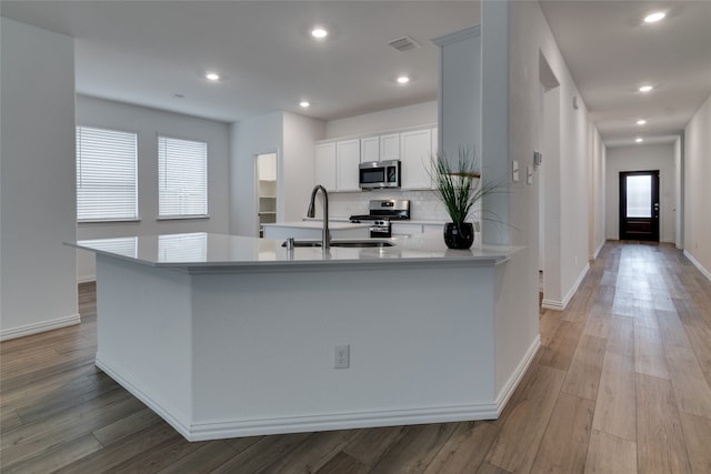 kitchen featuring white cabinets, light hardwood / wood-style floors, a healthy amount of sunlight, and appliances with stainless steel finishes