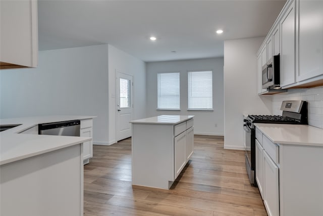 kitchen with white cabinetry, appliances with stainless steel finishes, a center island, and backsplash