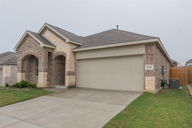 view of front facade with a garage, a front yard, and central air condition unit