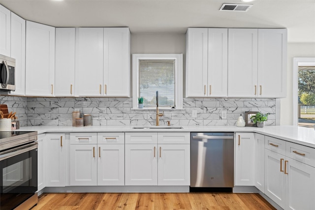 kitchen with white cabinetry, appliances with stainless steel finishes, light hardwood / wood-style floors, and sink