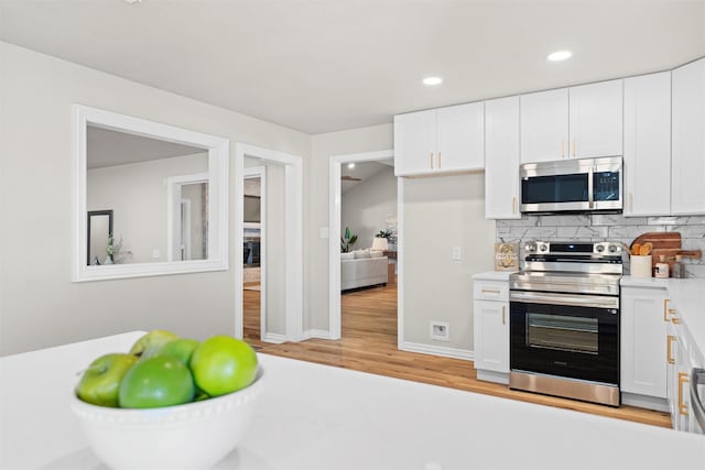 kitchen featuring backsplash, stainless steel appliances, light hardwood / wood-style floors, and white cabinets