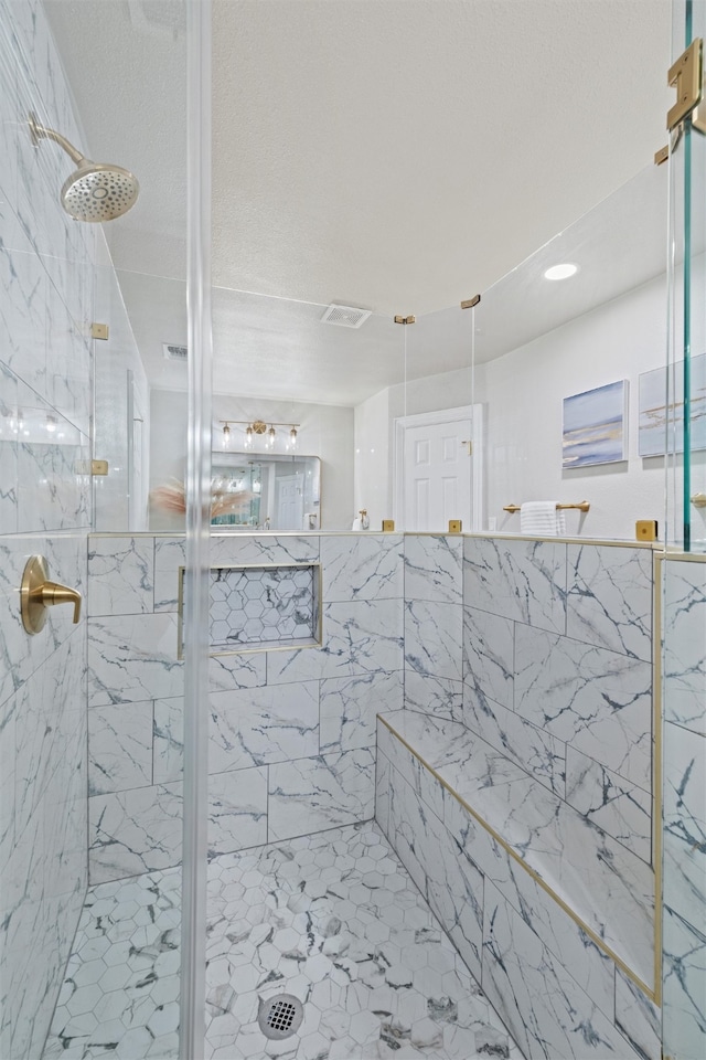 bathroom featuring a shower with shower door and a textured ceiling