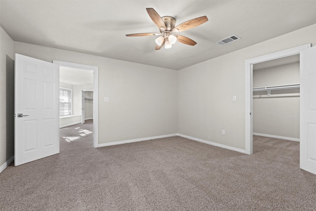 unfurnished bedroom with a closet, carpet flooring, ceiling fan, and a spacious closet