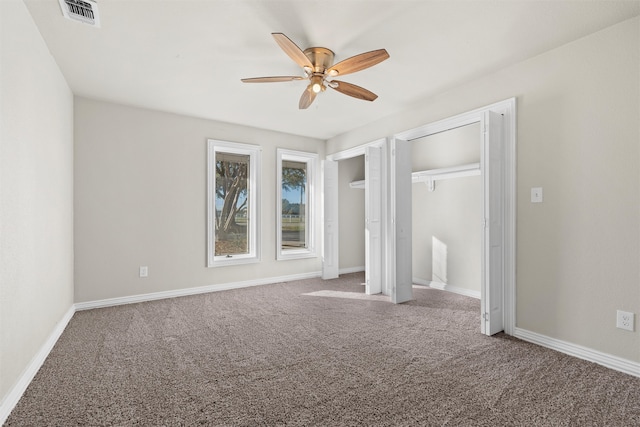 unfurnished bedroom with carpet flooring, two closets, and ceiling fan