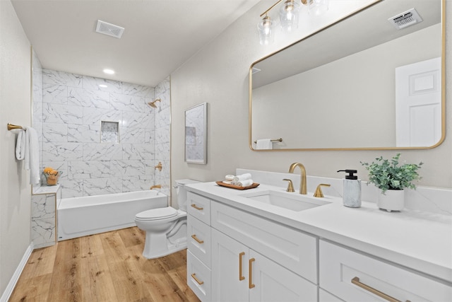 full bathroom featuring hardwood / wood-style flooring, tiled shower / bath, vanity, and toilet