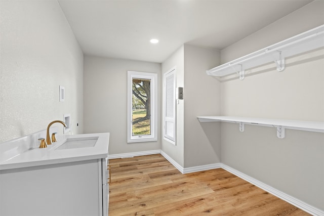 washroom featuring electric dryer hookup, sink, washer hookup, and light hardwood / wood-style flooring