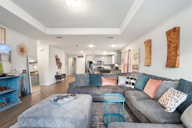 living room with a raised ceiling, dark hardwood / wood-style flooring, and ornamental molding