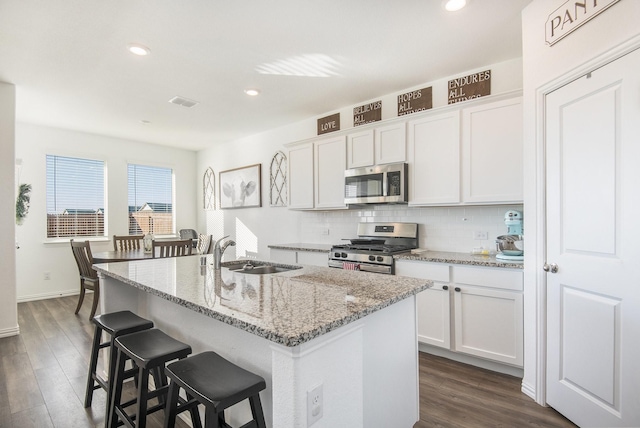 kitchen with an island with sink, sink, white cabinets, and stainless steel appliances