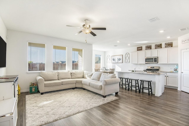 living room with ceiling fan and dark wood-type flooring