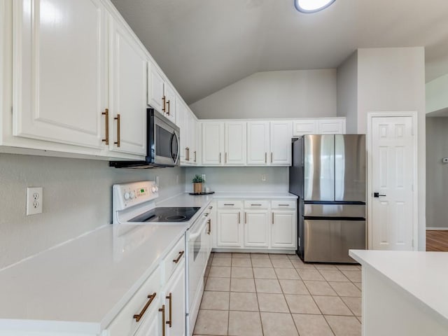 kitchen with stainless steel appliances, white cabinetry, lofted ceiling, and light tile patterned floors