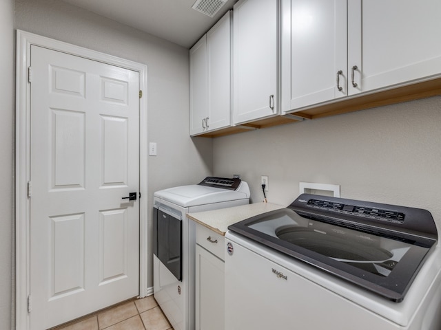 laundry room with cabinets, light tile patterned floors, and independent washer and dryer