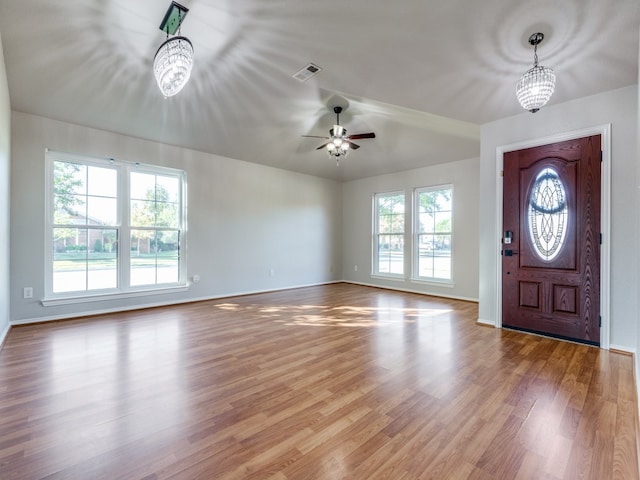 foyer entrance with hardwood / wood-style floors and ceiling fan with notable chandelier