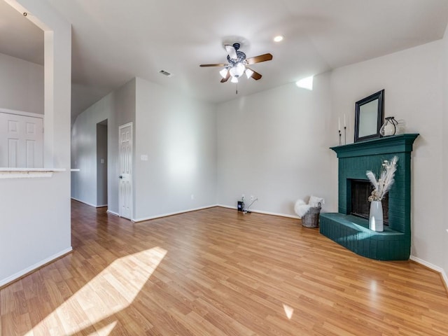 unfurnished living room with a brick fireplace, wood-type flooring, and ceiling fan