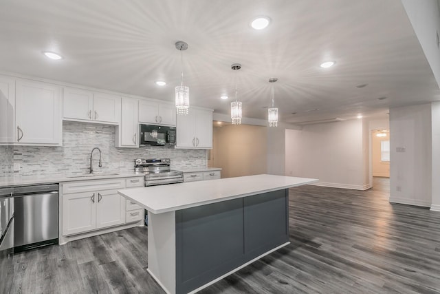 kitchen featuring appliances with stainless steel finishes, sink, white cabinets, hanging light fixtures, and a center island