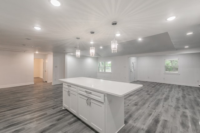 kitchen featuring wood-type flooring, decorative light fixtures, a kitchen island, and white cabinets