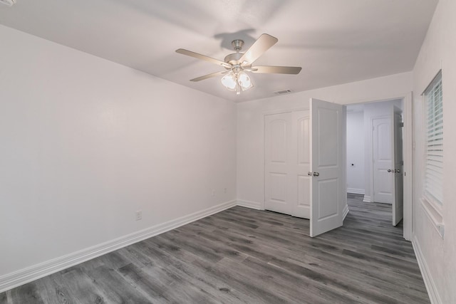 unfurnished bedroom featuring dark hardwood / wood-style floors, ceiling fan, and a closet