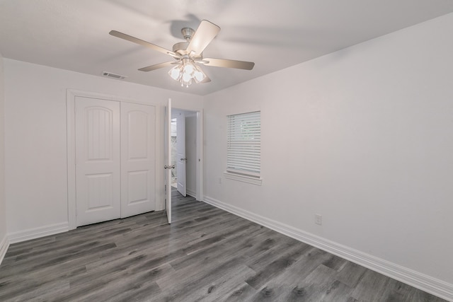 unfurnished bedroom featuring dark wood-type flooring, a closet, and ceiling fan