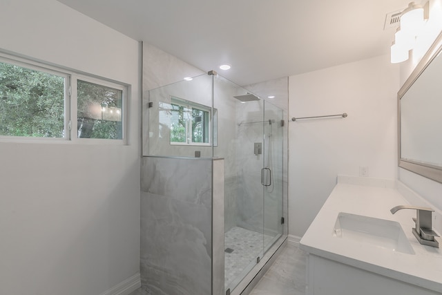 bathroom featuring a shower with door and vanity